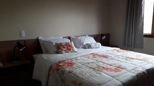 1 dormitorio con cama con edredón y almohadas en Pousada Recanto da Serra en São Pedro da Serra