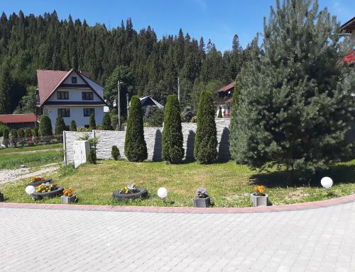 un jardin avec des arbres et une maison en arrière-plan dans l'établissement Noclegi u Pauliny i Pawła, à Nowy Targ