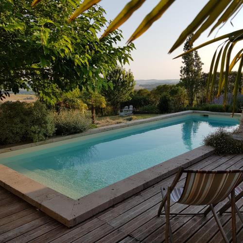 a swimming pool with a chair and a wooden deck at Propriété Le Monneton in Sainte-Christie