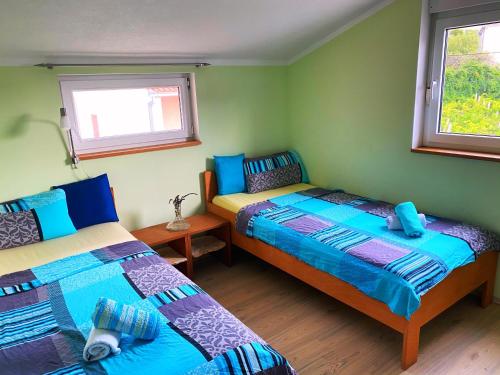 two beds in a room with two windows at Modern Red & Blue Apartment in Podstrana