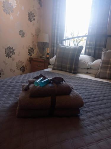 a bed with a pile of towels on it at Autumn Leaves Guest House in Windermere