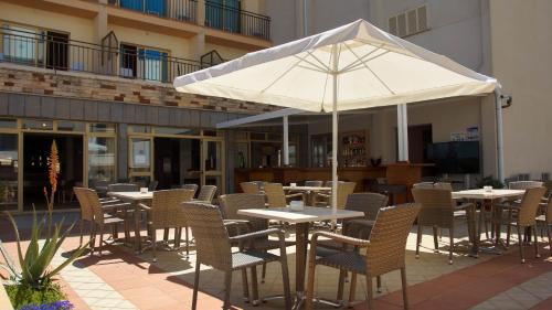 a patio table with umbrellas and chairs in front of a building at Hotel Iris in El Arenal