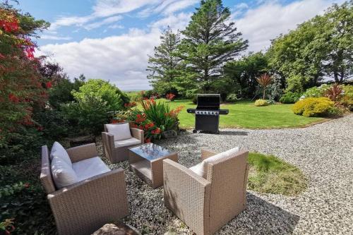 a patio with chairs and a grill in a yard at Cosy, Coastal Retreat with a Large Garden in Monreith