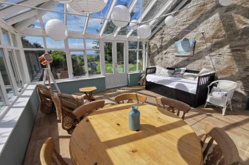 a conservatory with a table and chairs and a bed at Cosy, Coastal Retreat with a Large Garden in Monreith