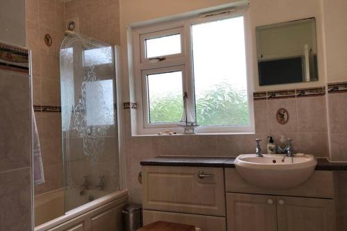a bathroom with a sink and a window and a tub and a mirror at Nyth Y Wiwer, Spacious and Peaceful Bungalow Near Harlech in Llanfair