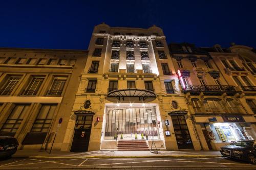 a large yellow building with lights on it at night at Mercure Lille Roubaix Grand Hôtel in Roubaix