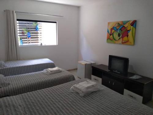 a room with two beds and a tv and a window at Thermas Hotel in Salgadinho