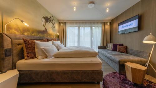 a bedroom with a large bed and a couch at ZillergrundRock Luxury Mountain Resort in Mayrhofen