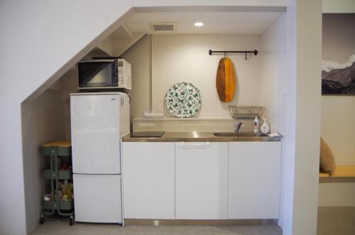 a kitchen with a white refrigerator and a sink at Travelers' house ROOTs in Takaoka