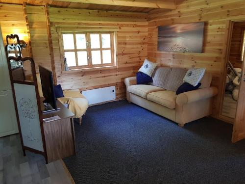 Cabaña con sala de estar con sofá y TV. en Cabin at Aithernie, en Leven