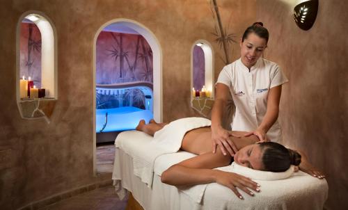 een vrouw die een massage krijgt van een vrouw die op een bed ligt bij Hotel Relax Torreruja Thalasso & Spa in Isola Rossa