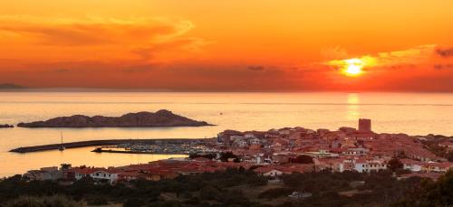a town with the sun setting over the ocean at Hotel Relax Torreruja Thalasso & Spa in Isola Rossa