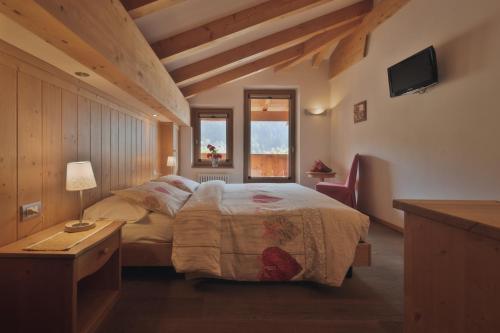 sypialnia z łóżkiem, stołem i oknem w obiekcie Dolomiti Hotel Cozzio w Madonna di Campiglio