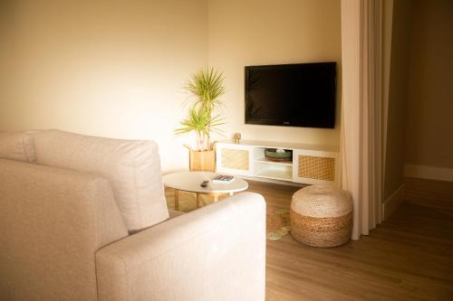a living room with a white couch and a tv at Ar d'Sal - Praia de Angeiras - Beach&GoodFood in Lavra