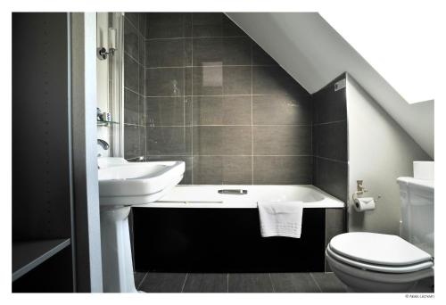 uma casa de banho com um lavatório, uma banheira e um WC. em Hotel De La Treille em Lille