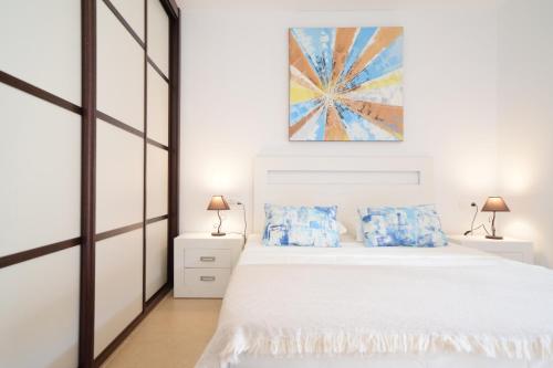 a bedroom with a white bed with blue pillows at Mocan Perfect Stay in Palm-Mar