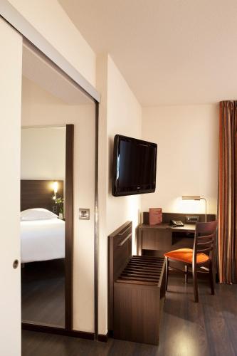 une chambre d'hôtel avec un lit et une télévision à écran plat dans l'établissement Escale Oceania Nantes Aéroport, à Bouguenais