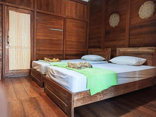 two beds in a room with wooden walls at Watukarung Prapto Homestay in Kalak