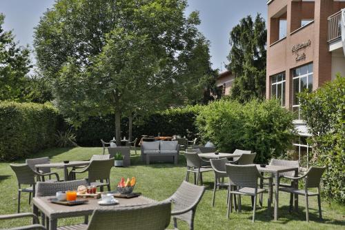 a patio with tables and chairs on the grass at B&B HOTEL Remilia in Reggio Emilia