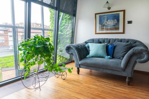 a living room with a couch and a potted plant at Aparthotel Hornigold "W Zielonej Kamienicy" in Katowice