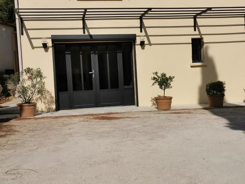 a black garage with two potted plants in front of it at Gîte 2 chambres avec piscine in Sernhac