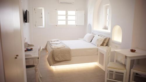 
a white bed sitting in a room next to a window at Paraporti in Chora Folegandros
