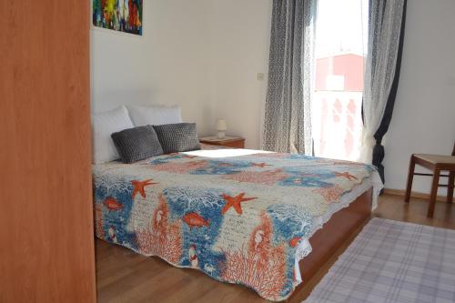 a bedroom with a bed with a colorful comforter and a window at Apartments Lucija in Srima