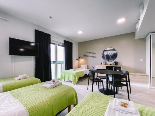 a room with two beds and a table and a mirror at Hotelli Kuohu Kangasala - Hotel and Apartments by UHANDA in Kangasala