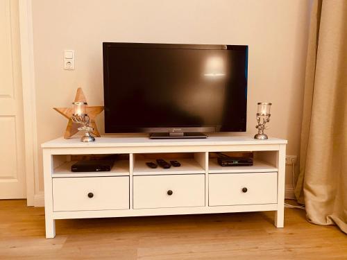 a white entertainment center with a flat screen tv on it at Mountain Suites Braunlage in Braunlage