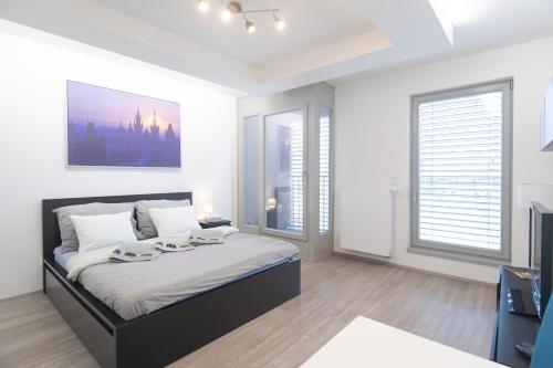 a white bedroom with a large bed and windows at Bright Studio, 10min Centre, Free Parking in Prague