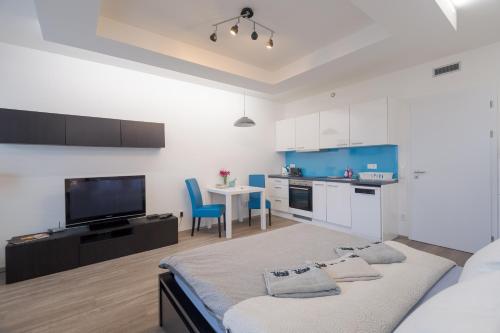 a bedroom with a bed and a kitchen with a tv at Bright Studio, 10min Centre, Free Parking in Prague
