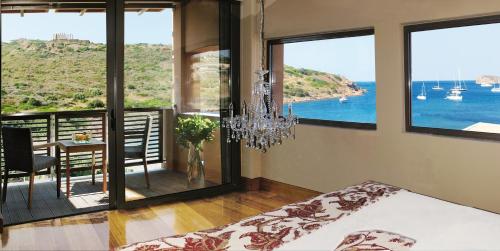 a bedroom with a chandelier and a view of the ocean at Aegeon Beach Hotel in Sounio