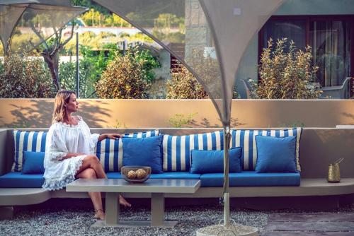 a woman is sitting on a blue couch at River Villas Parga in Parga