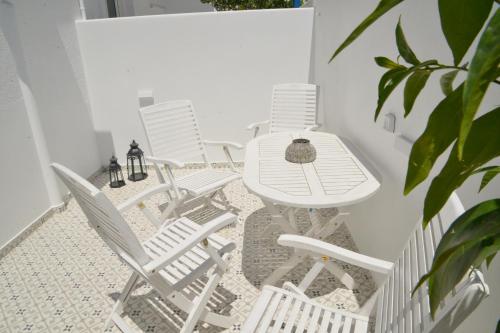 a group of white chairs and a table on a balcony at Veletas Rooms in Adamantas