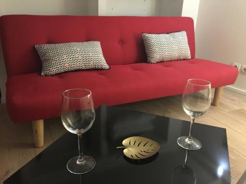 - un canapé rouge avec deux verres à vin sur une table dans l'établissement Lovely Studio, à Bourges