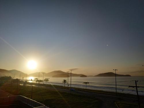 a view of the sun setting over a body of water at Ap frente para o mar in Caraguatatuba
