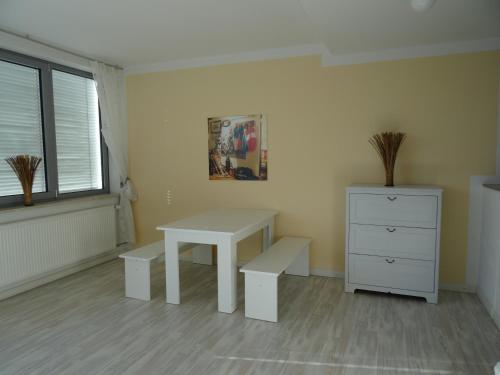 a white table and bench in a room with a dresser at Airport Park Hotel MUC in Hallbergmoos