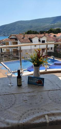 a table with wine glasses and a vase with flowers on it at Apartmani Niksic in Herceg-Novi