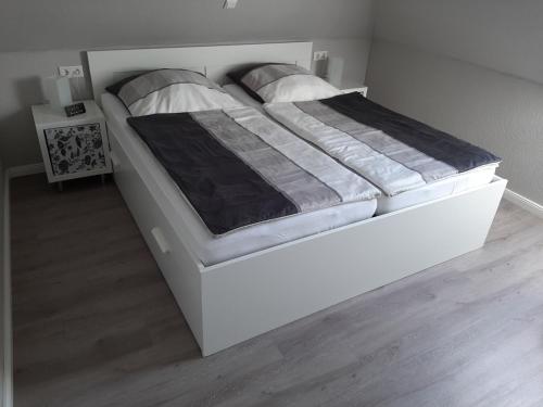 a large white bed in a room with wooden floors at Ferienwohnung im Schellenpark in Tarp