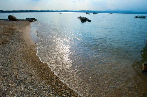 a beach with rocks and the water at San Francesco Camping Village in Desenzano del Garda
