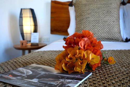 a book and a bouquet of flowers on a bed at Hotel Casa Terra in Villa de Leyva
