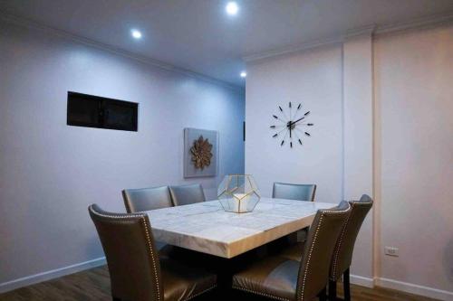 a dining room table with chairs and a clock on the wall at Franzon Apartment in Mactan