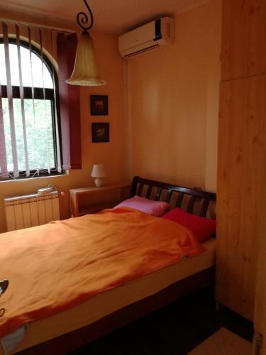 a bedroom with a bed with orange sheets and a window at Kuća na dan Villa Holiday in Sakule