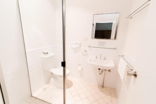 a white bathroom with a toilet and a sink at The Ophir Hotel in Orange