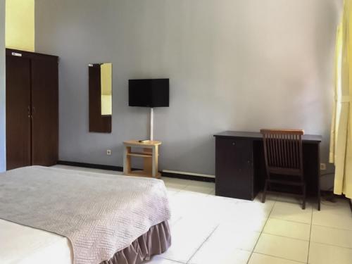 een slaapkamer met een bed, een bureau en een televisie bij Kemang Place near Lippo Mall Kemang Mitra RedDoorz in Jakarta