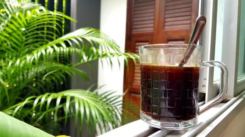 una taza de té de cristal sentada en el alféizar de la ventana en NIDO Guest House en Ban Bang Phang