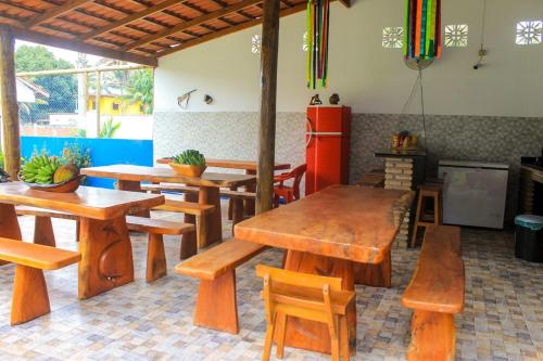 ein Restaurant mit Holztischen und -stühlen sowie einem Kühlschrank in der Unterkunft Recanto Calua in Serra Grande