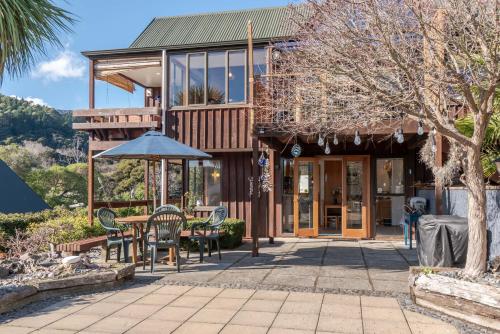 a house with a patio with a table and chairs at Pointers - Akaroa Holiday Home in Akaroa