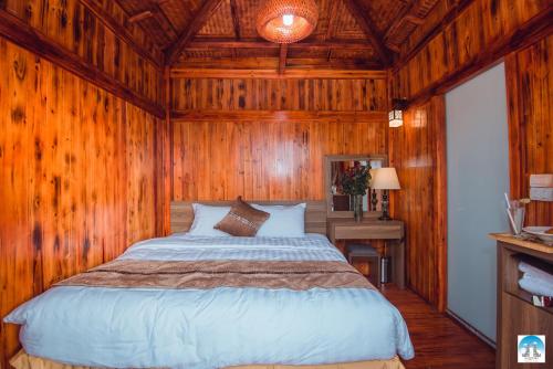 1 dormitorio con 1 cama y pared de madera en Heaven Gate Hotel O Quy Ho, en Lào Cai