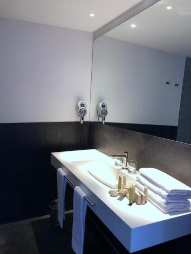 a bathroom with a sink with a mirror and towels at Le Pré du Moulin - Maison Alonso - Hôtel & Restaurant in Sérignan-du-Comtat